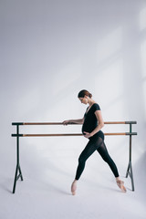 Young beautiful pregnant ballerina is posing in studio