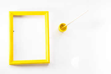 yellow wooden photo frame painted with gouache paint rough texture is next in a jar with a brush on...