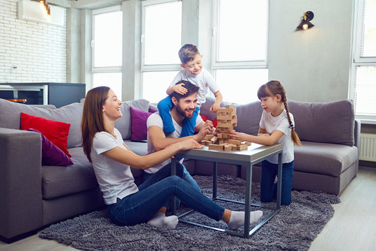Happy family playing board games at home. Mother, father and children play together.