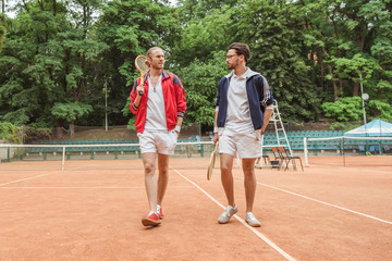 retro styled friends with wooden rackets walking on tennis court