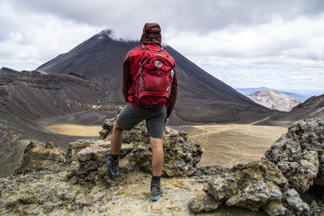 Travel New Zealand, Tongariro National Park. Young tourist hiker man overlooking volcanic landscape...