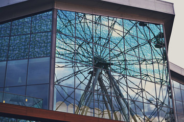Glass building which reflects the big wheel.