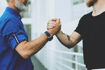 Two bearded entrepreneurs shaking hands as they glad to receive investment for the new start up...