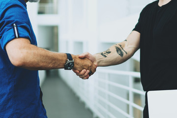 Two business partners dressed in casual wear shaking hands as they signed a contract after...