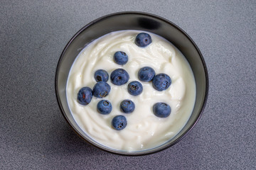 Top view on black bowl full of curd with blueberries 