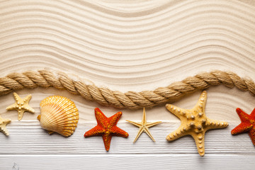 Fototapeta na wymiar Beach background - starfish, shell, rope and wooden plank on sand background