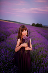 portrait of a girl with glasses, with long, beautiful and healthy hair on a lavender field with a bouquet of flowers.