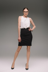 Fototapeta premium attractive businesswoman in eyeglasses posing on grey background