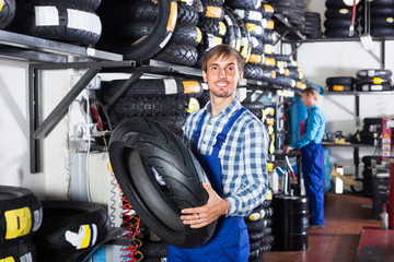 Fototapeta na wymiar worker holding new tyre