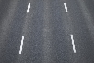 Fragment trzypasmowej drogi asfaltowej bez samochodów z namalowanymi białą farbą pasami
