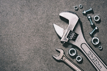 top view of monkey wrench, wrench and nuts on grey surface