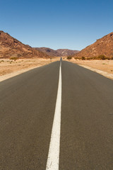 Fototapeta na wymiar Empty straight and long road in the Sahara Desert, South Algeria, North Africa 