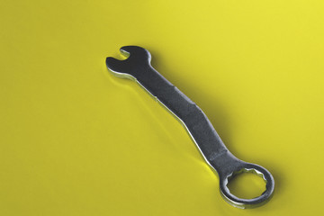 Metalowy klucz do śrub wyizolowany na żółtym tle