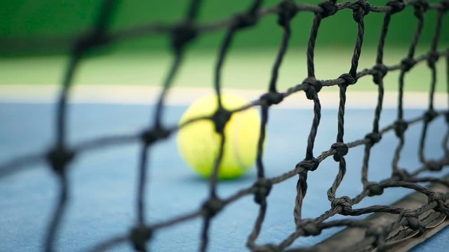 Close up of tennis equipment on the court. Sport, recreation concept. Yellow tennis balls hit the net on a clay green blue court next to the white line with copy space and soft focus