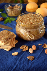 Fototapeta na wymiar Urbech of apricot kernels in a glass jar and on a cracker