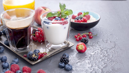Many different fruits and berries. Vitamins and healthy food. Orange juice in a glass, Yogurt, muesli with berries and fragrant morning coffee. Tasty breakfast. Copy space,