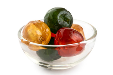 Red, green and yellow glace cherries in glass bowl isolated on white.