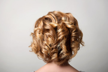 Hairstyle short curls on the head of a blonde view from behind.A woman's hairdo.