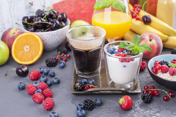 Many different fruits and berries. Vitamins and healthy food. Orange juice in a glass, Yogurt, muesli with berries and fragrant morning coffee. Tasty breakfast. Copy space.