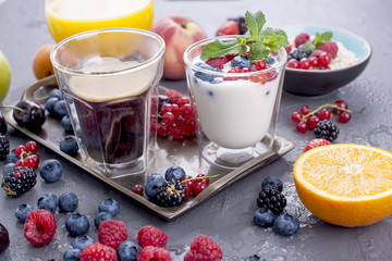 Many different fruits and berries. Vitamins and healthy food. Orange juice in a glass, Yogurt, muesli with berries and fragrant morning coffee. Tasty breakfast. Copy space.