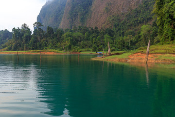 Obraz premium Reflection of mountains on the water lake of mist with many fog over the lake.Morning landscape of nature reflection at khao sok thailand