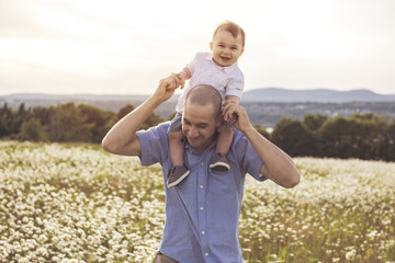 little boy and his father enjoying outdoors in field of daisy flowers