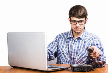 guy with glasses on the phone sitting at the computer