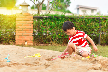 Asian boy playing with sand in playground
