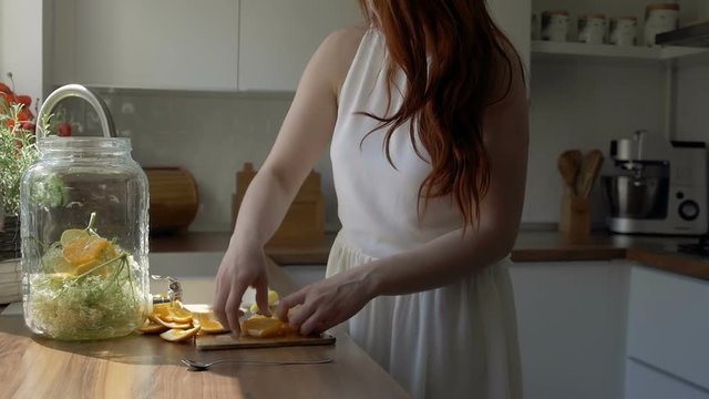 Young woman preparing tasty lemonade in kitchen, wide shot