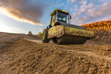 Yellow steamroller on road in sunlight