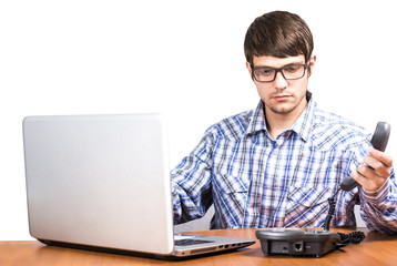 guy with glasses on the phone sitting at the table with a computer