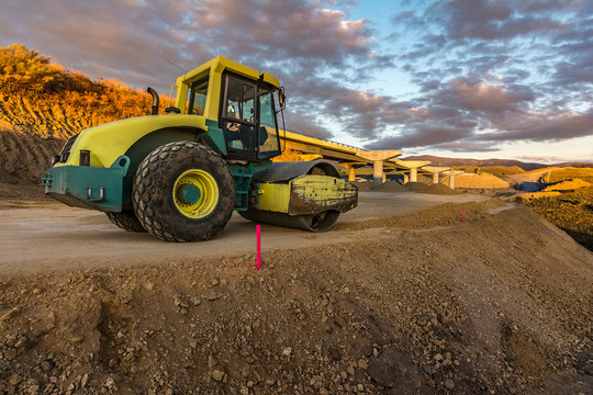 Yellow steamroller on road in sunlight