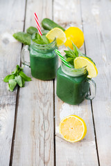  green smoothie with straw in a jar mug on a wooden background.