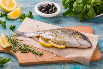 Fresh fish dorado. Spicy herb and vegetables healthy food spice on black stone board cooking.