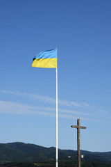 Ukraine flag and christian cross, Khust city background. View from ruin of old castle. Landscape, Zakarpattia Oblast. Ukraine.