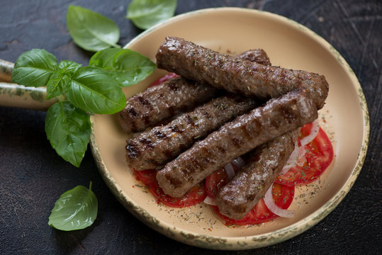 Barbecued cevapcici or skinless beef sausages served with tomatoes and onion, traditional dish in the Balkans, horizontal shot