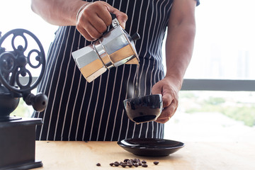 Barista coffee moka concept. Moka coffee pot to make espresso on hand. barista pour espresso from moka pot. Coffee in vintage tone.