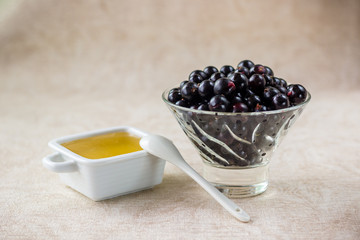 black currant in a glass bowl and honey in a white dish