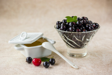 black currant in a glass bowl, red cherry and honey in a white dish
