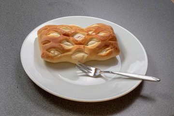 Braun gebackenes Teilchen mit einer Kuchengabel auf einem weißen Teller