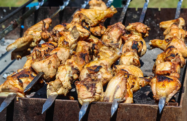 Appetizing delicious fried pieces of meat on skewers are roasted on a large grill in the open air.
