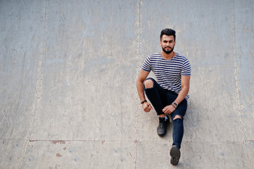 Handsome tall arabian beard man model at stripped shirt posed outdoor. Fashionable arab guy.