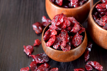 Dried cranberries in wooden bowls against the dark background