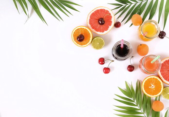Assortment of natural juices in glass jars of oranges, grapefruit, cherries and various fruits on a white backgroundtop view. copy space