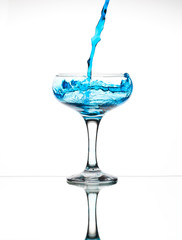Splash from pouring blue water into the champagne glass