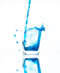 Splash from pouring blue water into the glass on white background