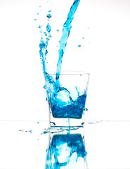 Splash from pouring blue water into the glass