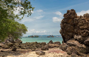 a stone cape. boats in the blue sea.