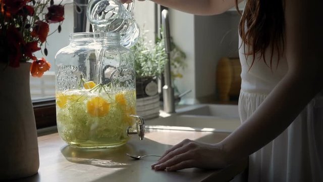 Young woman pouring water on freshly made lemonade, slider shot