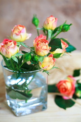 beautiful bouquet of roses in glass on wooden table , selective focus